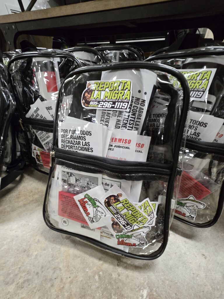 Clear bags packed with printed outreach materials: Reporta la Migra stickers, know your rights flyers and red cards, ready to hand out.